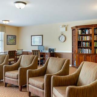 A cozy library room with armchairs, bookshelves, and computers.