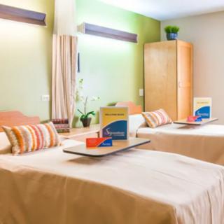 A cozy hotel room with two neatly made beds, each with a tray and colorful pillows.