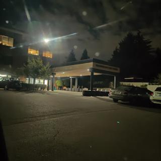 A quiet street scene at night with illuminated buildings and parked cars.