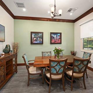 A cozy dining room with wooden furniture, colorful wall art, and a soft green accent wall.