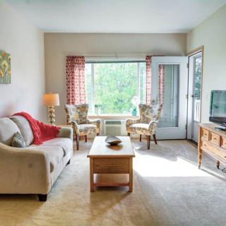 A cozy living room with a sofa, chairs, coffee table, and large window.