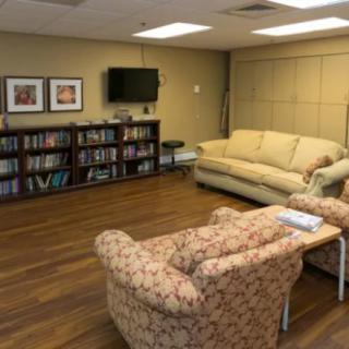 A cozy living room with sofas, a bookshelf, and a wall-mounted TV.