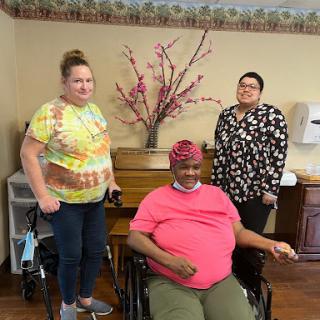 A joyful moment shared among three individuals in a care facility.