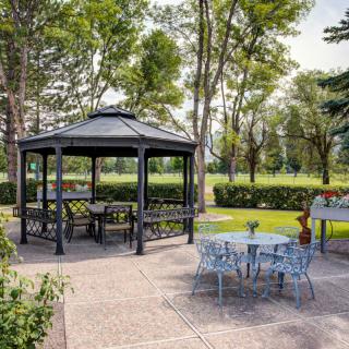 A cozy outdoor space with a gazebo, surrounded by lush greenery and garden furniture.