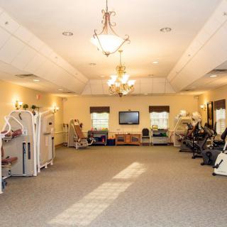 A spacious gym with various exercise equipment and bright lighting.