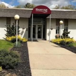 A building entrance with a red awning and landscaped walkway.