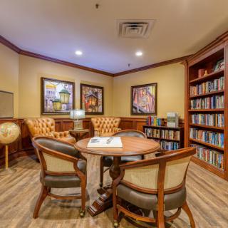 A cozy library reading area with bookshelves, a table, and comfortable seating.