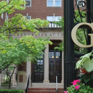 A building entrance surrounded by greenery with a decorative gate.