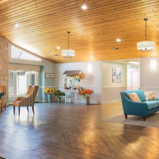 A spacious and elegantly designed living room with a wooden ceiling, modern furniture, and ample natural lighting.