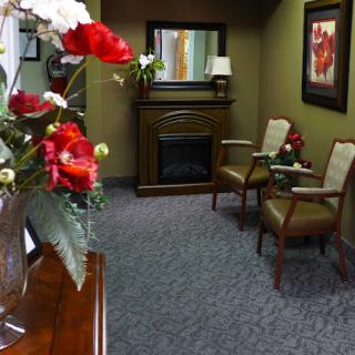 A cozy waiting room featuring comfortable chairs, decorative flowers, and a fireplace.