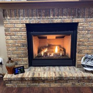A cozy brick fireplace with a warm fire burning inside.