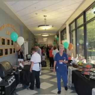 A hallway event with people, balloons, and food tables on display.