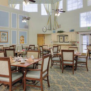 A well-lit dining room with arranged tables and chairs, featuring large windows and elegant decor.