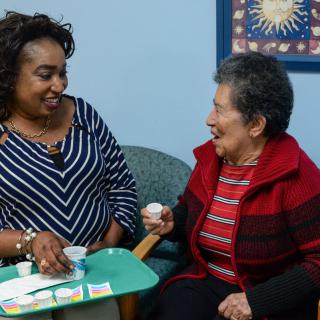 A caregiver and an elderly woman enjoying a friendly interaction in a healthcare setting.