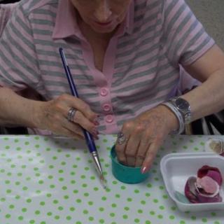 A woman engages in a hands-on art project using a paintbrush.