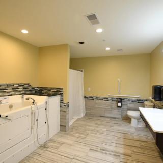 A spacious and modern bathroom with a bathtub, toilet, and sink, featuring stylish tile flooring and ample lighting.