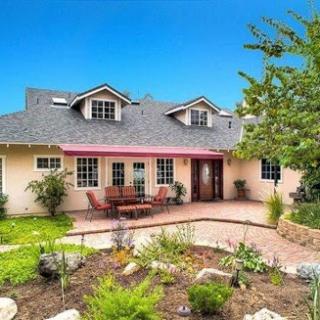 A charming residential home featuring a well-kept garden and inviting outdoor seating.