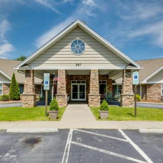 A commercial building entrance with stone columns and a well-maintained parking area.