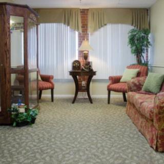 A well-decorated living room with a cozy ambiance, featuring a sofa, chairs, table, and lamp.
