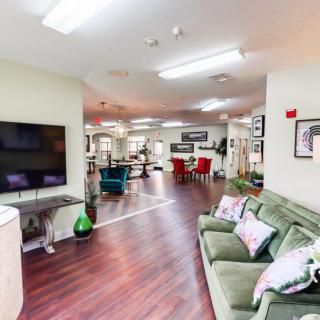 A spacious and modern living area with wooden flooring, a large TV, and a comfortable green sofa.