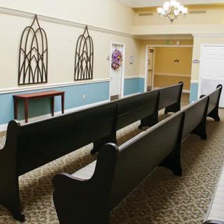 A small chapel with rows of dark wooden pews and decorative wall elements.