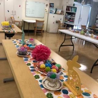 A classroom decorated for Easter with colorful crafts and ornaments on tables.