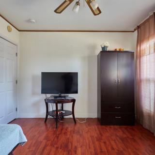 A simple bedroom setup featuring a television on a small table, a wardrobe, and wooden floors.