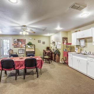 A cozy dining and kitchen area with a table set for four, surrounded by carpeted flooring and homey decor.