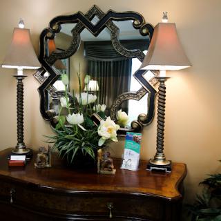 A beautifully arranged decorative piece featuring elegant lamps, a stylish mirror, and fresh flowers.