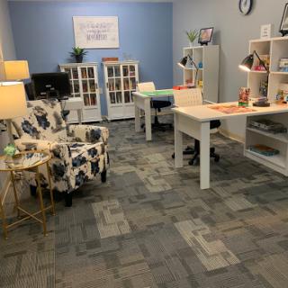 A well-organized modern office space featuring a workspace with desks, lamps, and decorative elements.