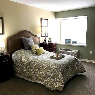 A cozy bedroom with a neatly made bed, decorative pillows, and warm lighting.