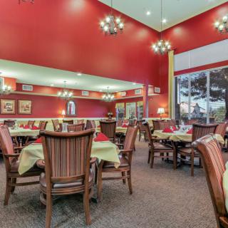 An elegantly decorated restaurant dining area with red walls, chandeliers, and neatly arranged tables and chairs.