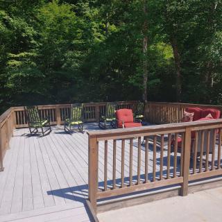 A spacious outdoor deck with seating, surrounded by trees on a sunny day.