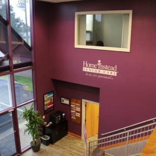 A view of a building's interior lobby area with a staircase, window, and signage on the wall.