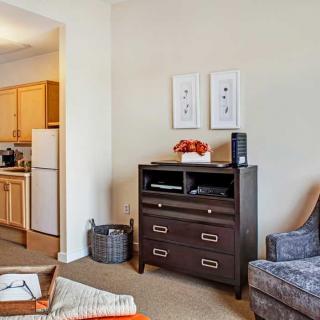 A cozy living room area with a view into the kitchen, featuring a cabinet, chair, and decorative accents.