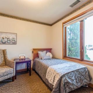 A cozy bedroom with a single bed, adjacent chair, and large window overlooking the outdoors.