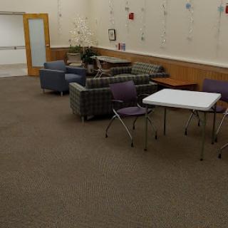 A cozy lounge area with chairs and tables, designed for relaxation or waiting.