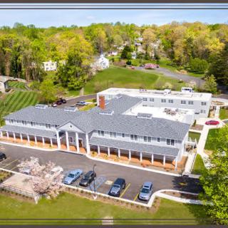 Aerial view of a suburban building with a parking lot surrounded by trees and roads.
