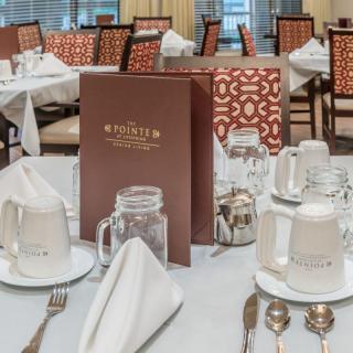 An elegant dining room setup with neatly arranged place settings and a menu on display.