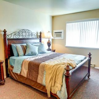 A cozy bedroom with a wooden bed frame, soft lighting, and neatly arranged pillows.