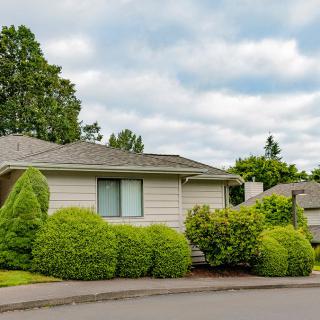 A suburban house with a lush garden and cloudy sky.