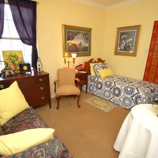 A cozy bedroom with a single bed, decorated with framed art and soft lighting.