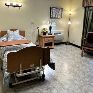 A clean and organized hospital patient room with a single bed and medical equipment.