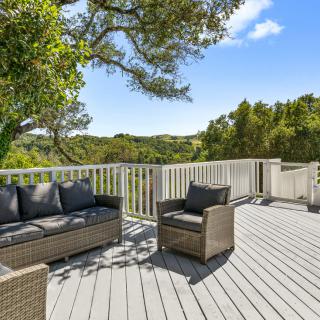 A scenic outdoor deck with comfortable seating, surrounded by lush greenery and trees.