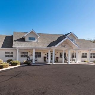 A large residential building with a driveway under a clear blue sky.