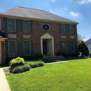 A suburban brick house with a well-maintained lawn on a sunny day.