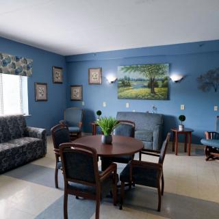 A cozy living room with blue walls, featuring a sofa, chairs, a table, and decorative wall art.
