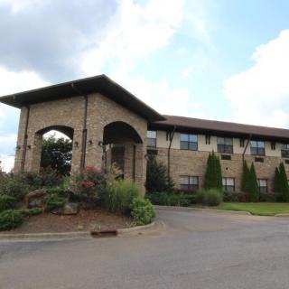 A two-story brick building with landscaped surroundings under a partly cloudy sky.