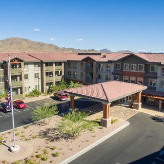 A multi-story residential building set against a desert landscape with mountains in the background.