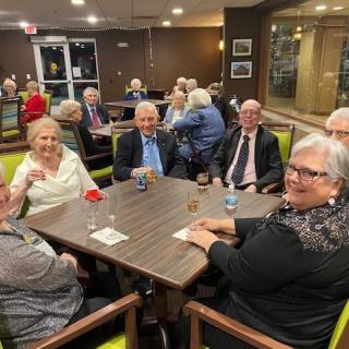 A group of seniors enjoying a social gathering at a dining table indoors.